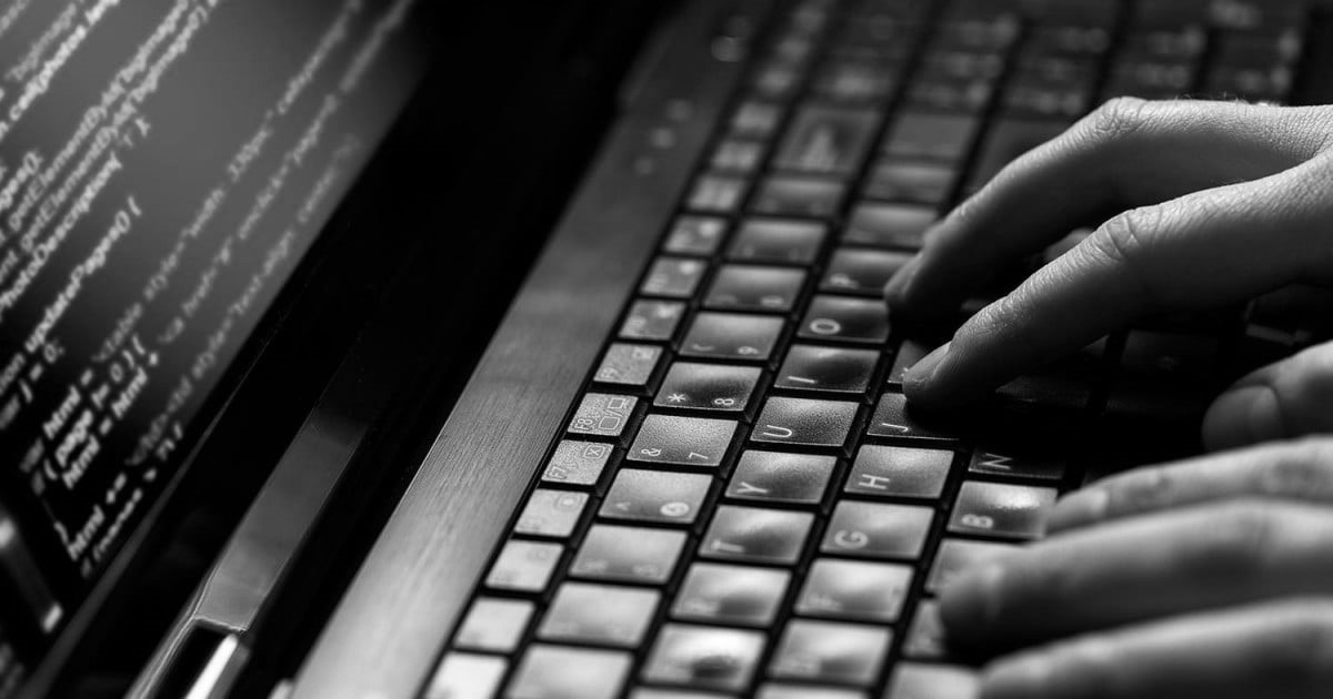 Közelkép, ahogyan valaki gépel a laptopján, a képernyőn programkódokkal